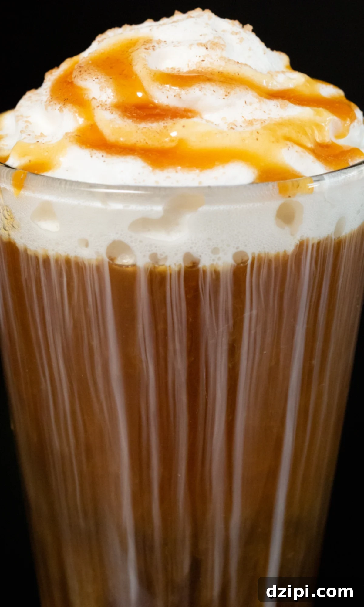 A close-up shot of a stunning Caramel Apple Cold Brew, adorned with thick whipped cream and a luxurious caramel drizzle, served in a pint glass, captured against a sophisticated black backdrop.