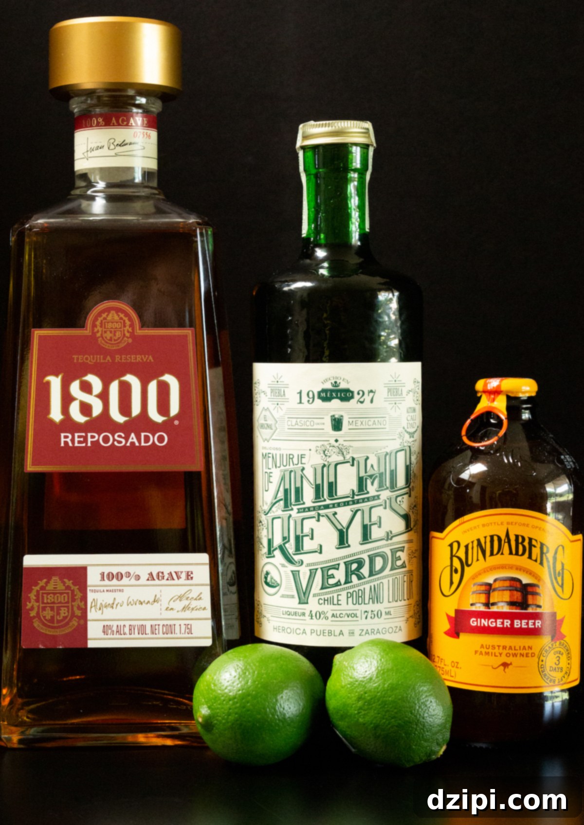 A visually appealing flat lay showing all the key ingredients for Mexican Mules: tequila, chile liqueur, fresh limes, simple syrup, and ginger beer, arranged neatly on a sleek black background.