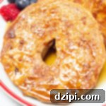 Maple Glazed French Toast Bagel 7 A sliced bagel that has been turned into french toast sits on a plate next to fresh berries.