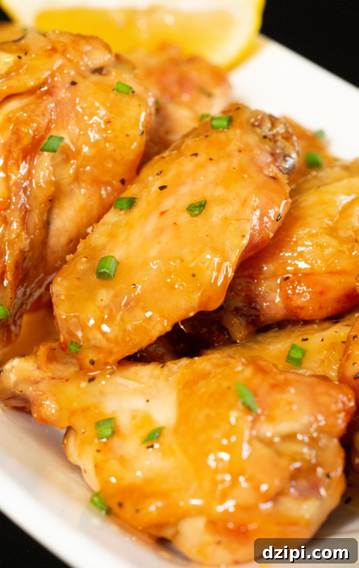 Close up shot of several honey lemon pepper chicken wings stacked, highlighting their crispy texture and shiny glaze.