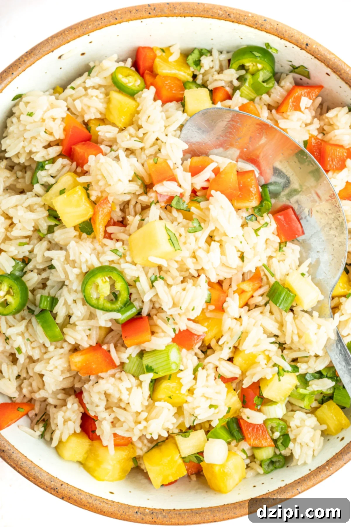 A bowl filled with fluffy Instant Pot coconut rice, generously topped with diced pineapple, vibrant red bell pepper, and thinly sliced jalapeños.