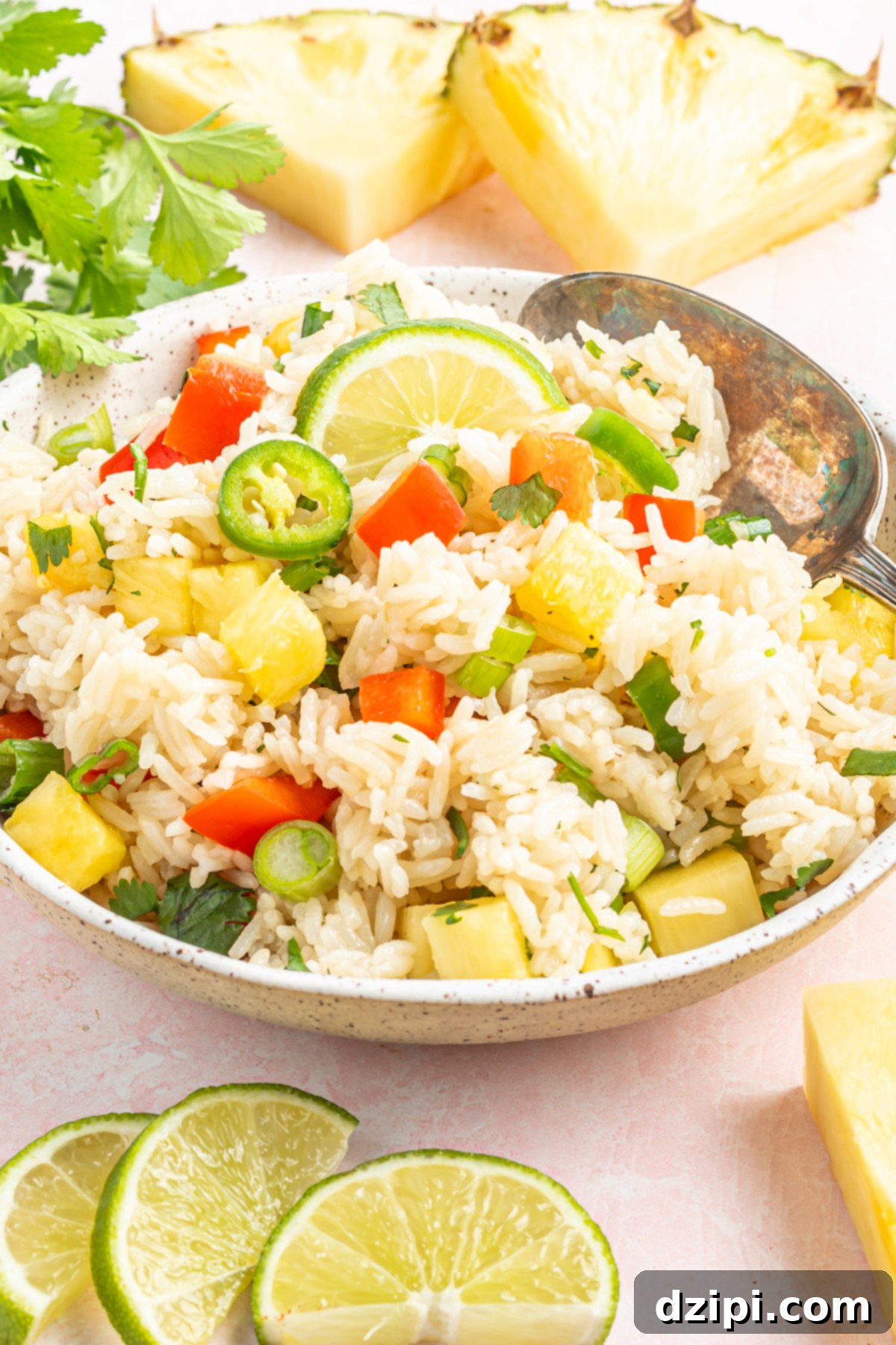 A vibrant serving bowl brimming with Instant Pot coconut rice, adorned with a colorful array of chopped pineapple, green onions, jalapeño slices, and red bell pepper.