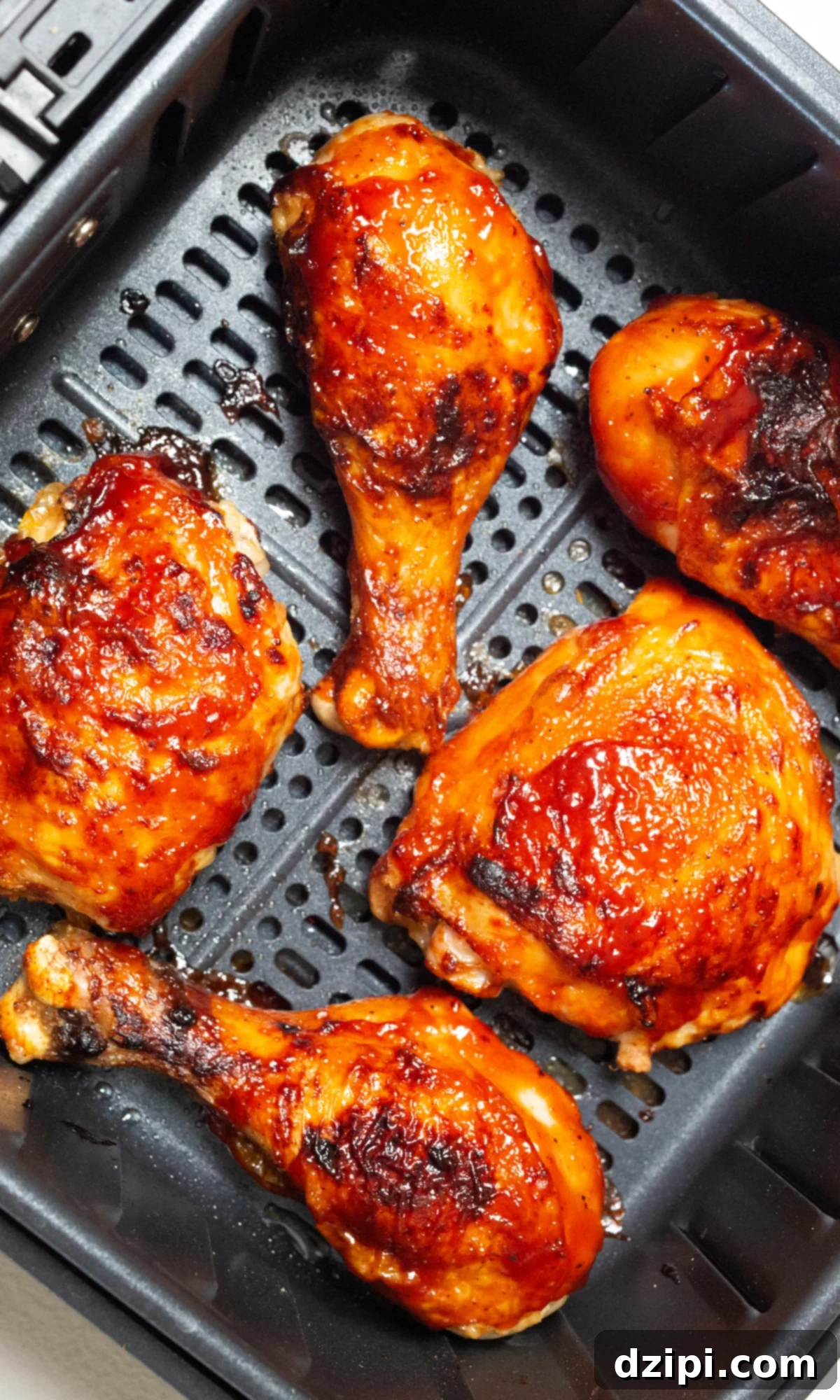Crispy and juicy BBQ chicken legs and thighs, freshly cooked in an air fryer basket, ready to be served.