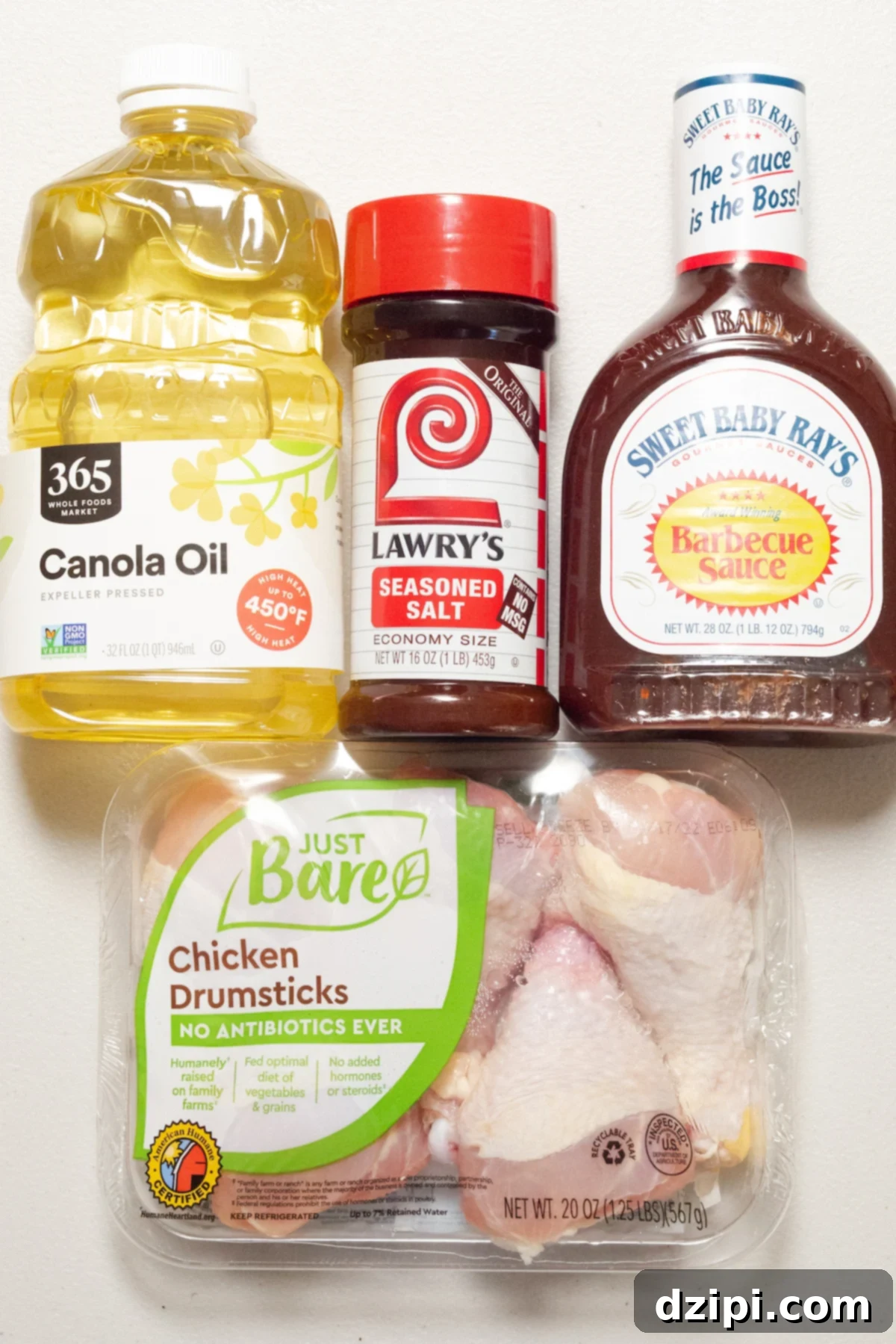 A simple arrangement of ingredients for air fryer BBQ chicken, including chicken pieces, seasoning, oil, and BBQ sauce.