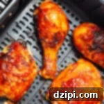 Cooked BBQ chicken legs and thighs in an air fryer basket, garnished and ready to serve.