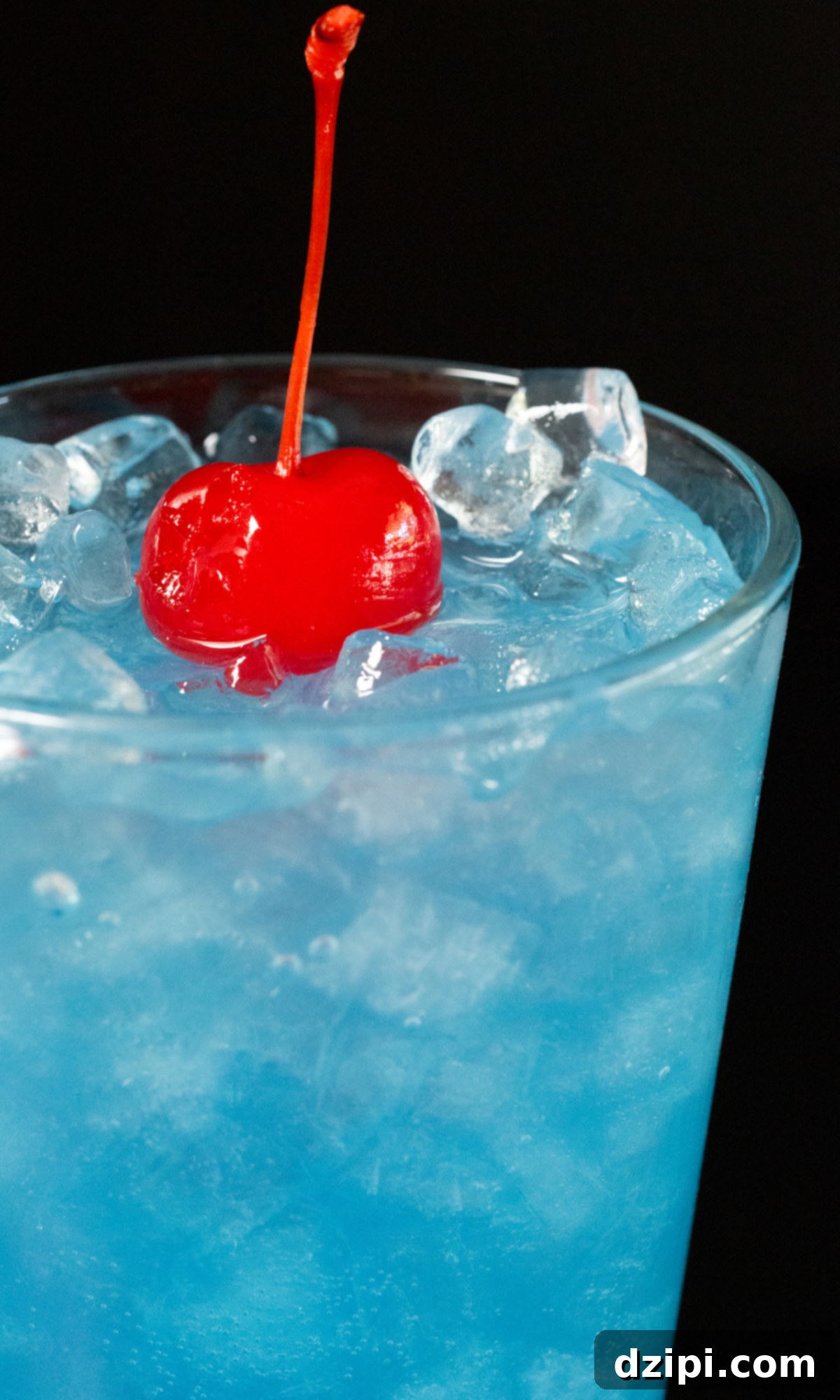 The Endless Blue 5 A close-up of a glass of blue Ocean Water, garnished with a bright red maraschino cherry on top.