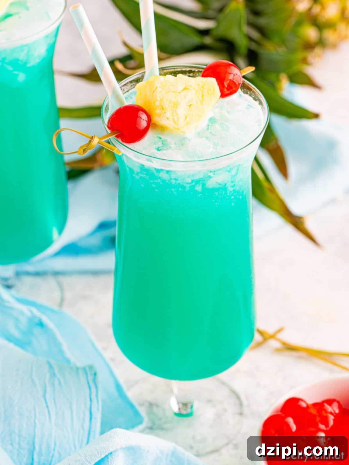 A tall glass filled with a vibrant blue Blue Hawaiian cocktail, perfect for a tropical beach escape.