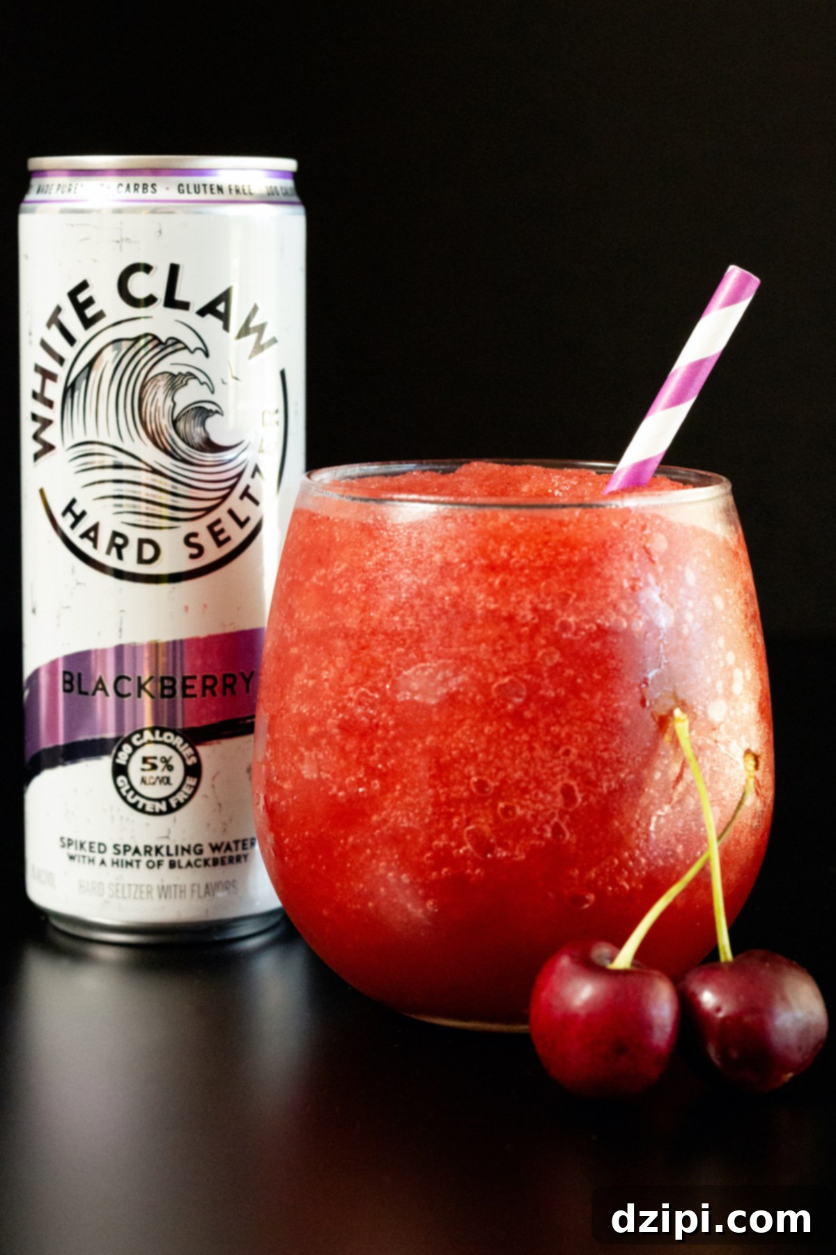 A stemless wine glass filled with a vibrant red White Claw Slushie, with a White Claw can in the background on a sleek black surface.