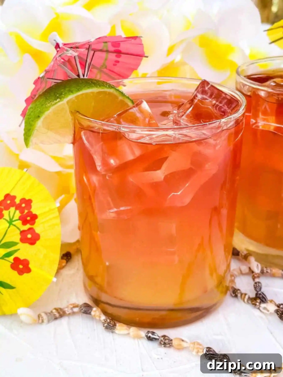 A short glass filled with a refreshing Malibu Bay Breeze cocktail, garnished with a lime wedge and a charming drink umbrella.