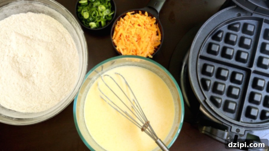 Overhead view of Cheddar Waffle BAE Breakfast Sandwich ingredients and a waffle maker ready for cooking