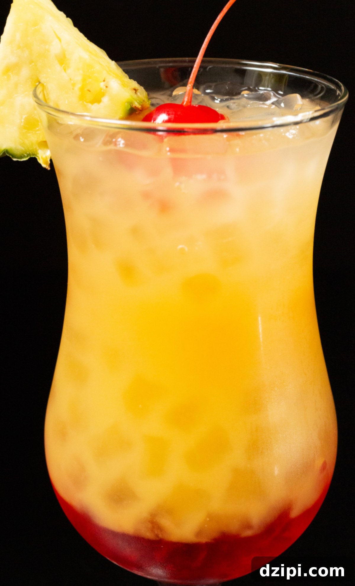 A close-up of a perfectly crafted Bahama Momma cocktail, garnished with a pineapple wedge and maraschino cherry, in a hurricane glass.