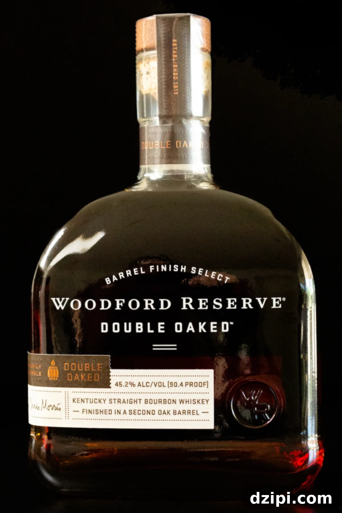 A bottle of Woodford Reserve Double Oaked bourbon on a black background, highlighting its rich amber hue.