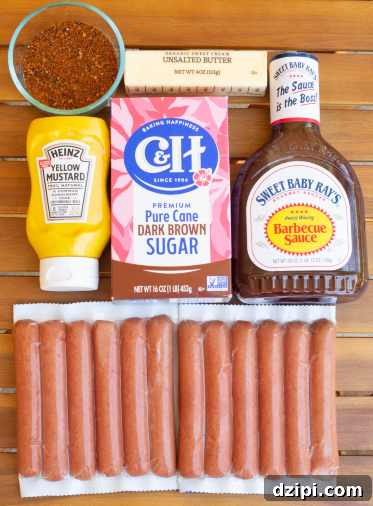 All the ingredients to make hot dog burnt ends laid out on a wooden outdoor table.