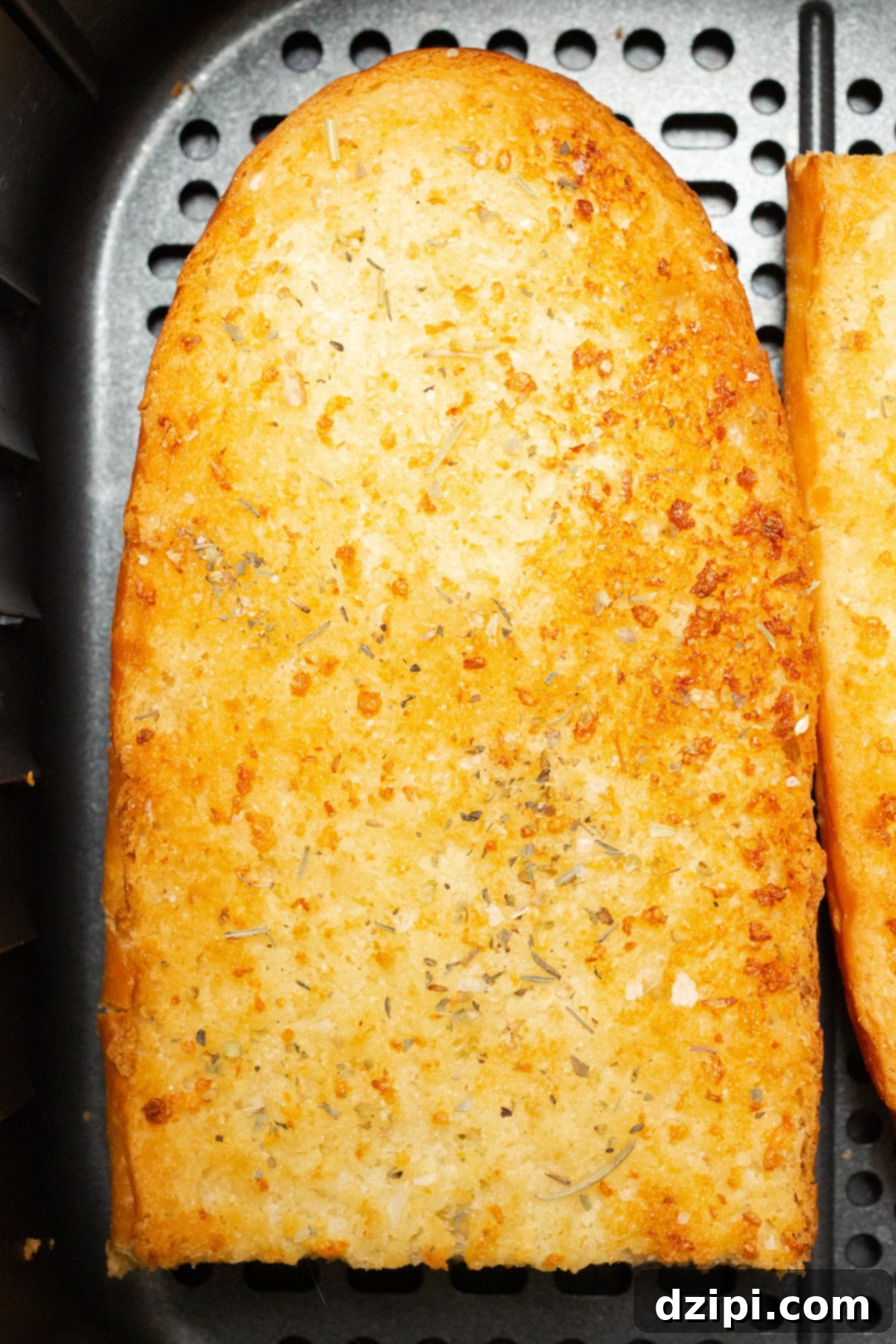 A perfectly cooked piece of air fryer garlic bread, golden and crispy, resting in an air fryer basket.