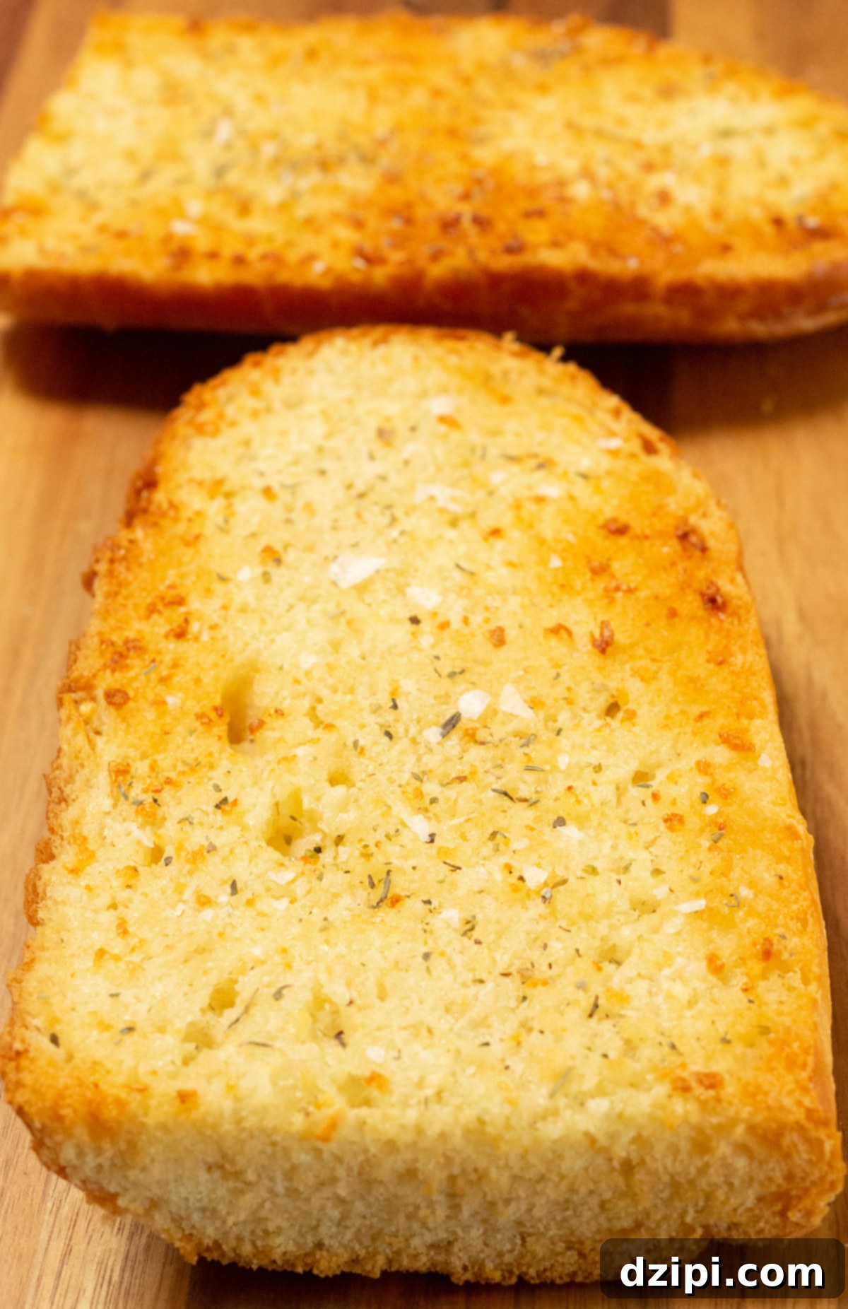Two pieces of golden, perfectly toasted air fryer garlic bread on a wooden cutting board, ready to be served.