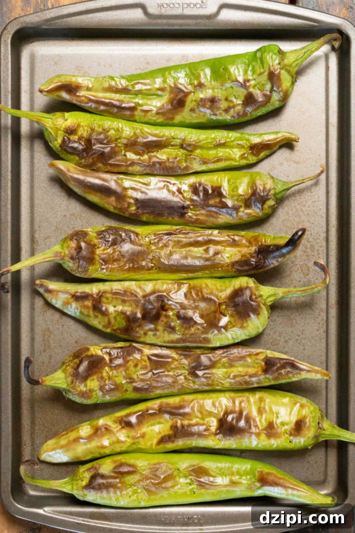Charred Hatch Chiles 2 Overhead view of a baking sheet filled with bright green roasted Hatch Chiles, ready to be peeled.