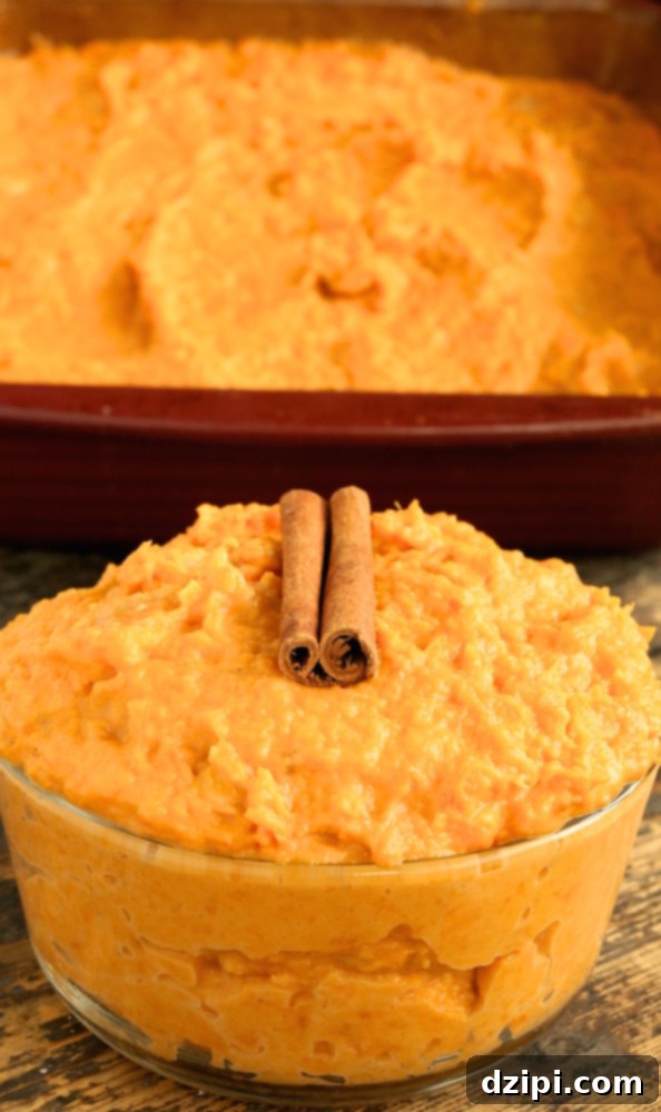 A glass serving bowl of Thanksgiving sweet potatoes sits in front of a baking dish.