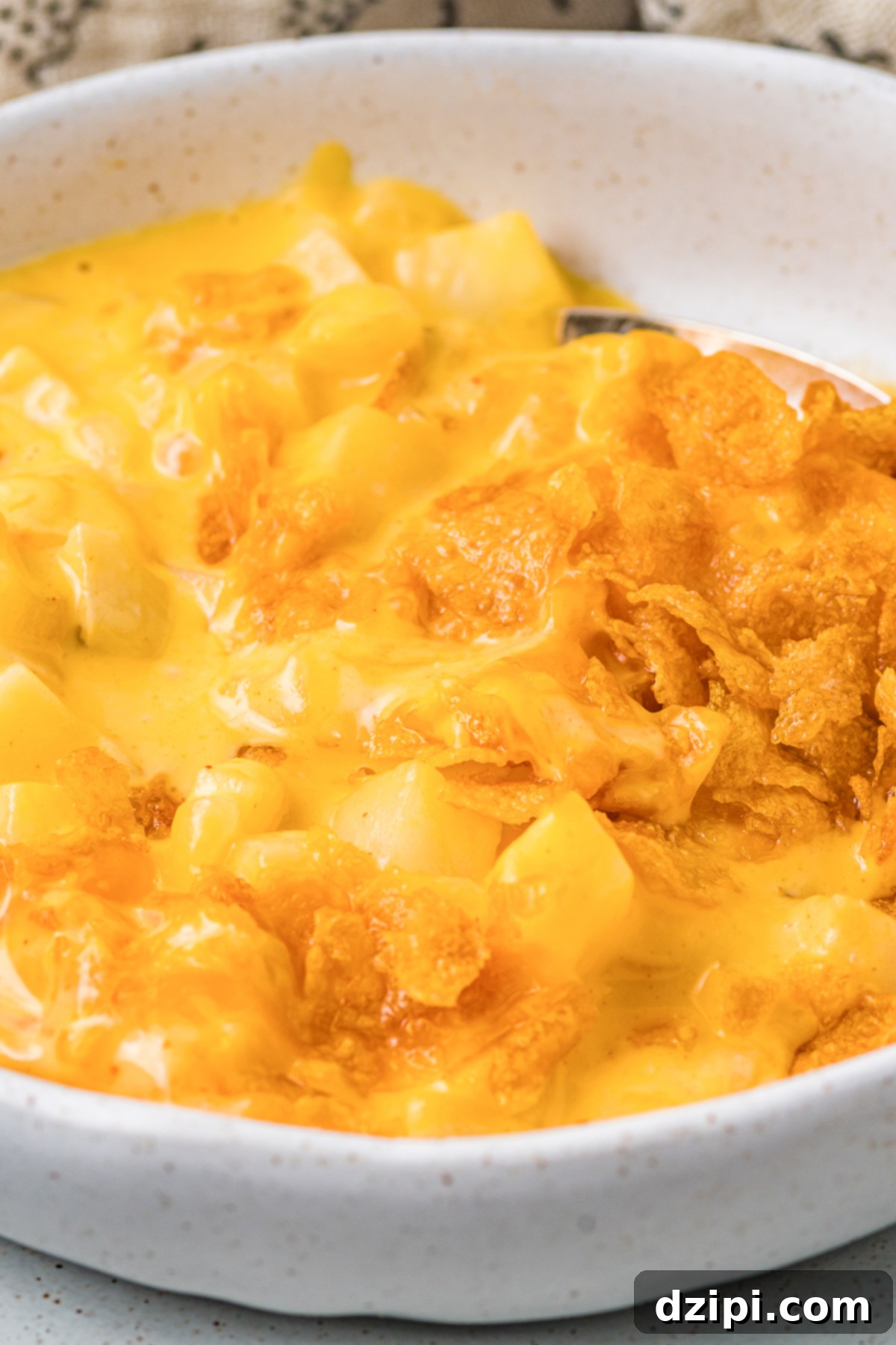 Close up of a serving of cheesy hash brown casserole in a white bowl.