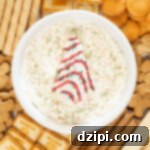 Holiday Tree Cake Dip 8 Overhead view of a platter with a bowl of Little Debbie's Christmas Tree Cake Dip in the center surrounded by a variety of cookies.