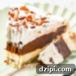 A slice of layered possum pie sits on a pale green serving dish. A fork with the end of the pie on it rests next to the slice.