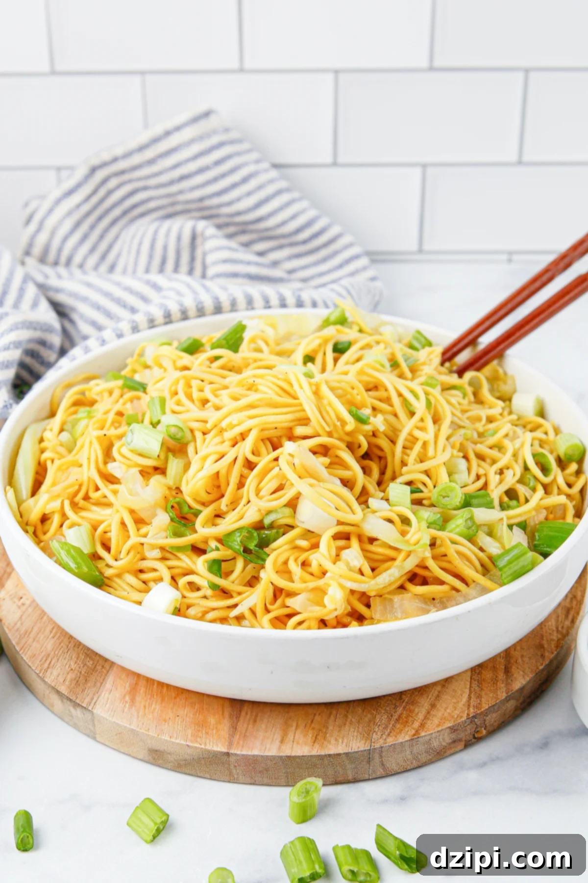 Iconic Panda Express Chow Mein 3 A shallow white serving bowl filled with perfectly stir-fried chow mein noodles, garnished with freshly sliced green onion and accompanied by chopsticks.