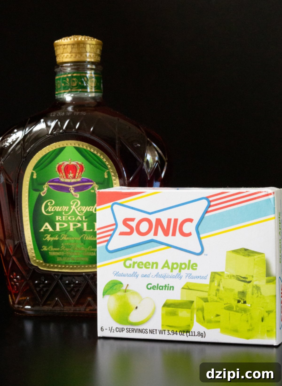A bottle of Crown Apple whisky and a box of Sonic green apple gelatin on a black background.