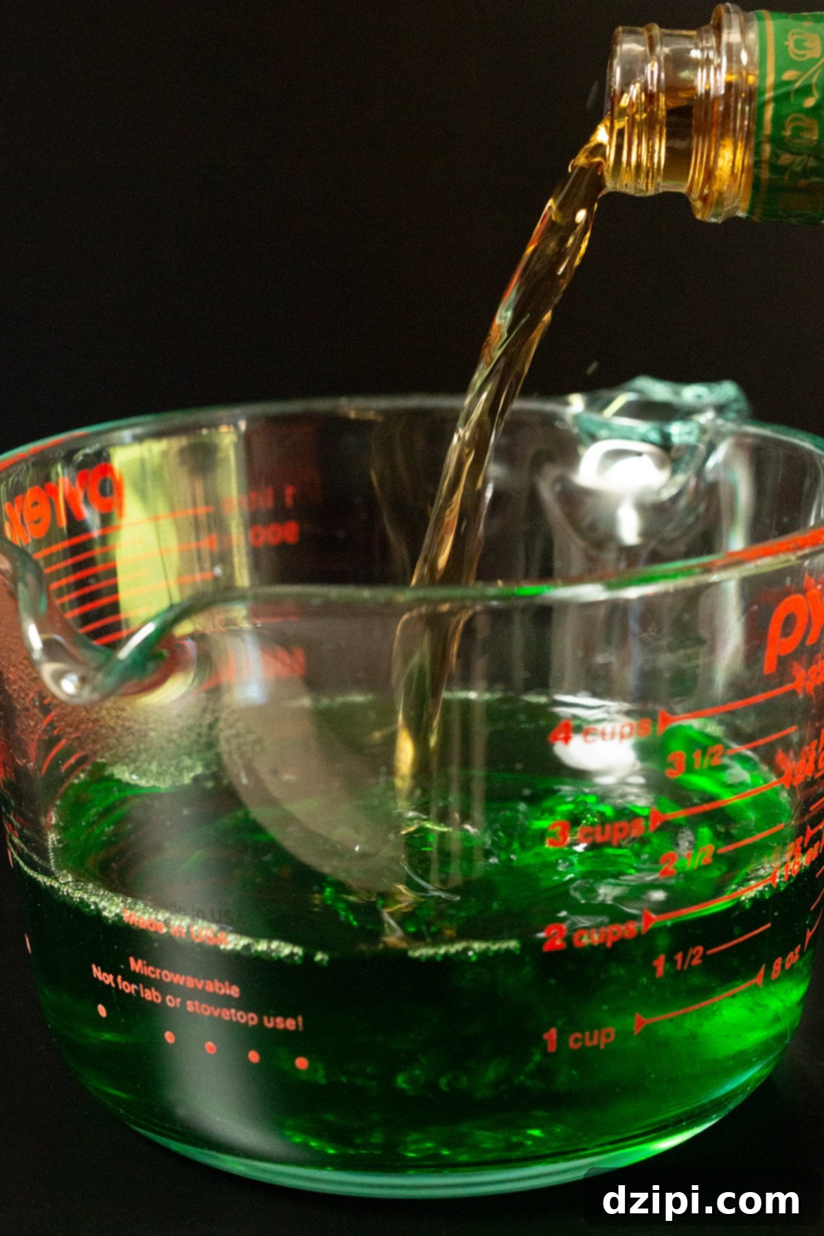 Crown Apple whisky poured from the bottle into a large measuring cup with green apple gelatin.