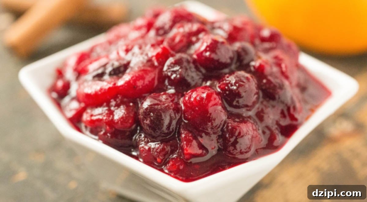 Vibrant cranberry compote in an elegant white serving dish, garnished with fresh cranberries and a sprig of rosemary for the holidays.