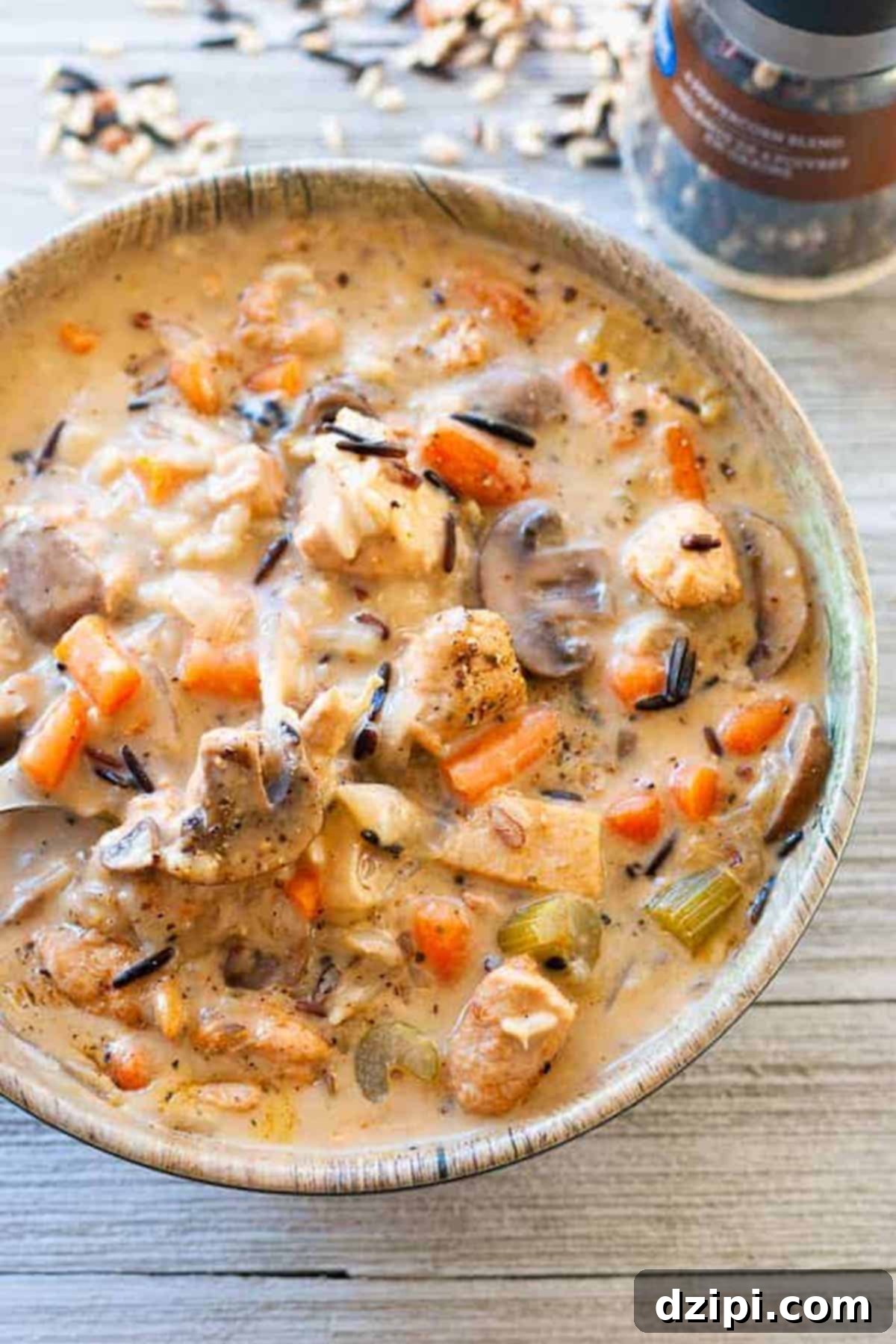 A large, inviting bowl filled with creamy chicken and wild rice soup, featuring perfectly cooked wild rice, sliced mushrooms, tender celery, and bright carrots, promising a satisfying meal.