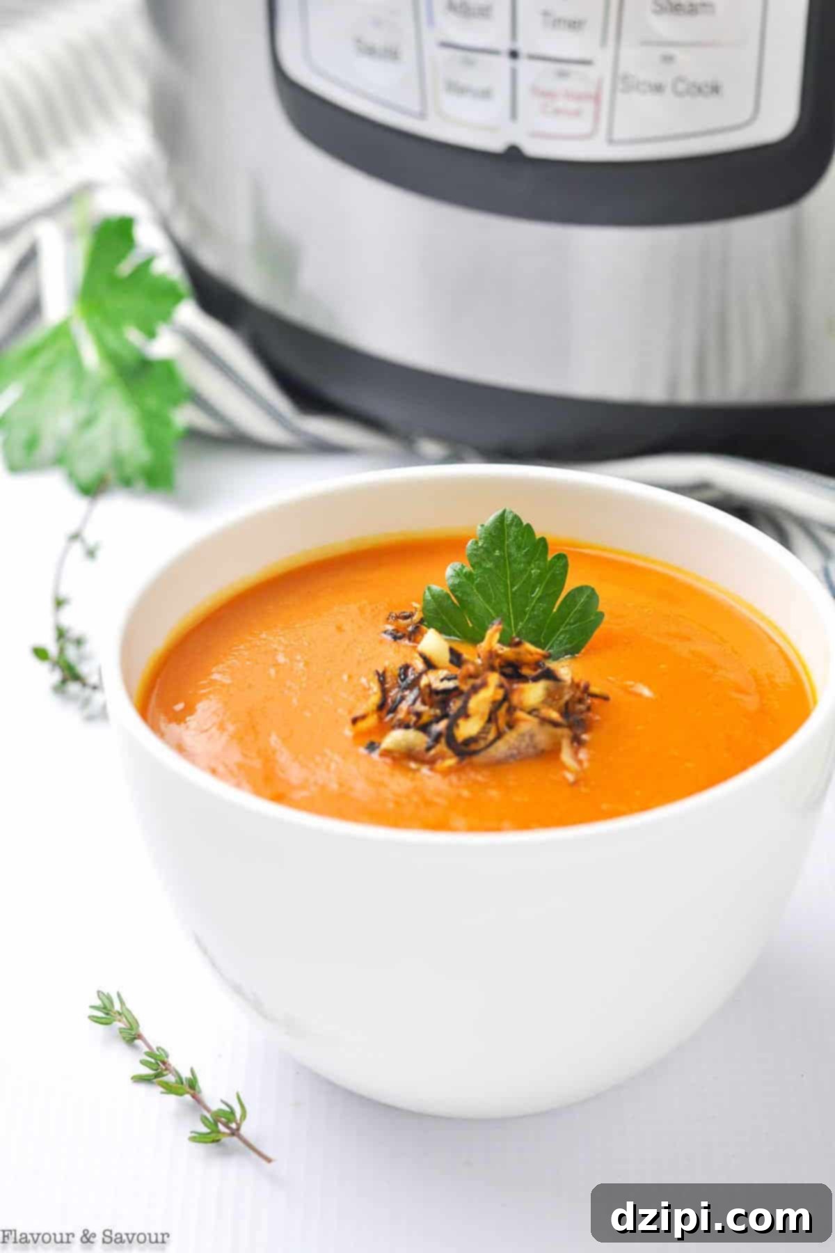 A pristine white soup bowl filled with bright orange, velvety smooth carrot & ginger soup, prominently displayed in front of an Instant Pot, highlighting its fresh preparation.