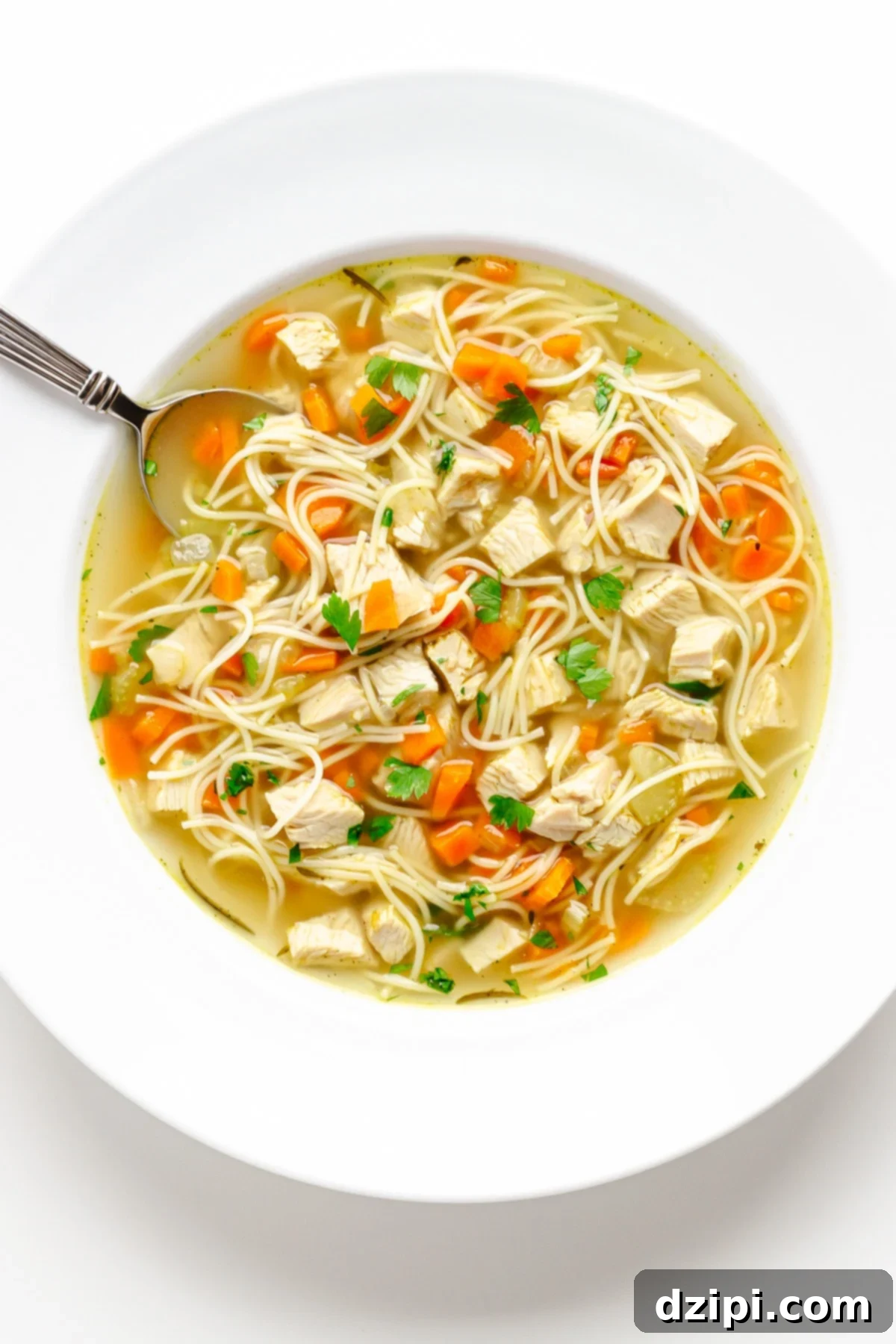 A large, inviting white soup bowl filled to the brim with wholesome Instant Pot turkey soup, showcasing tender turkey meat, a medley of fresh vegetables, and flavorful noodles.