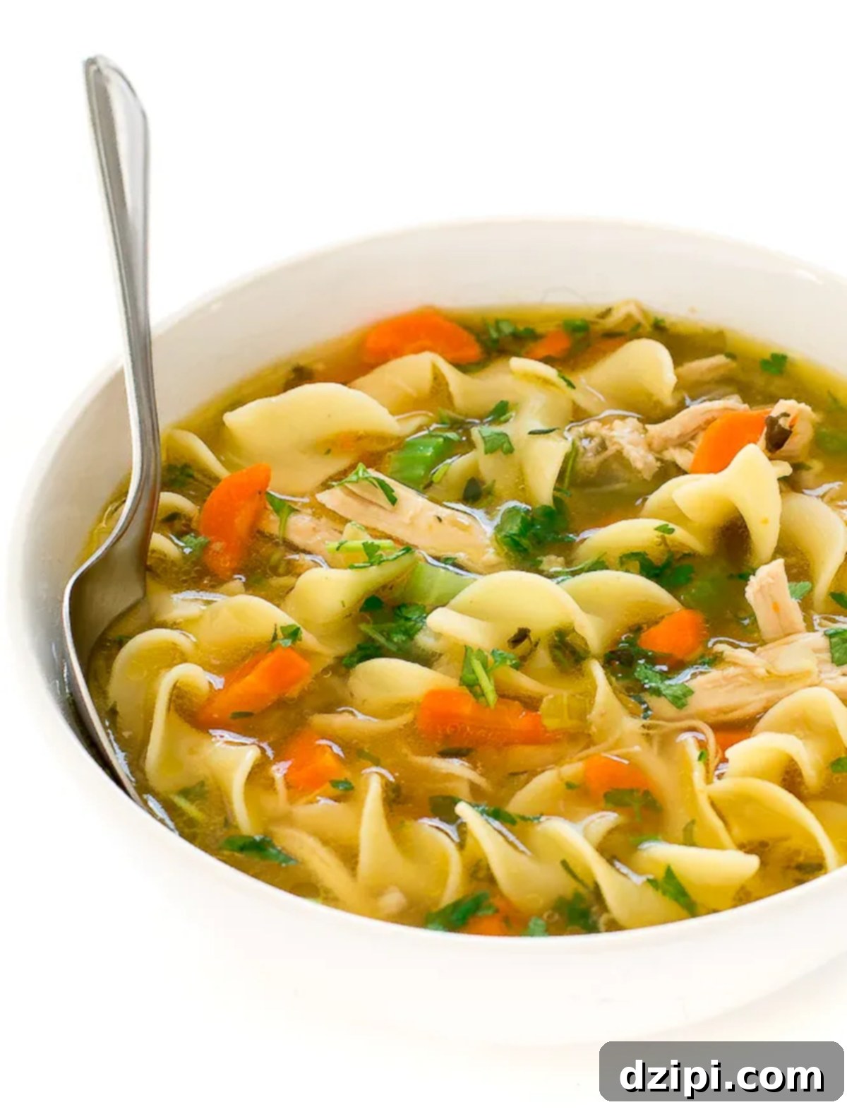 A beautifully presented bowl filled with classic Instant Pot chicken noodle soup, featuring tender chicken, golden egg noodles, and vibrant vegetables, all on a clean white background.