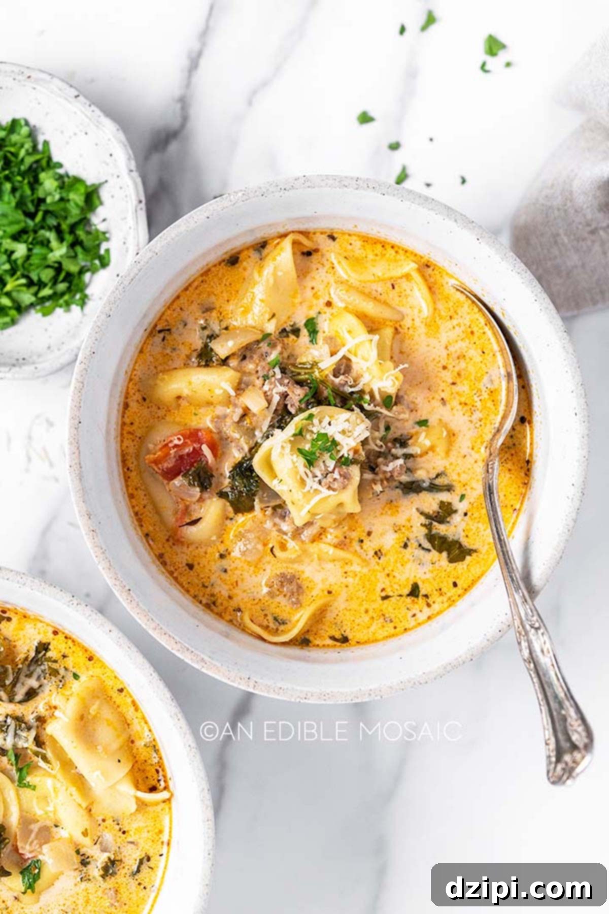A pristine white bowl overflowing with creamy tortellini soup, elegantly garnished with a sprinkle of fresh, chopped parsley, adding a vibrant touch to the rich dish.
