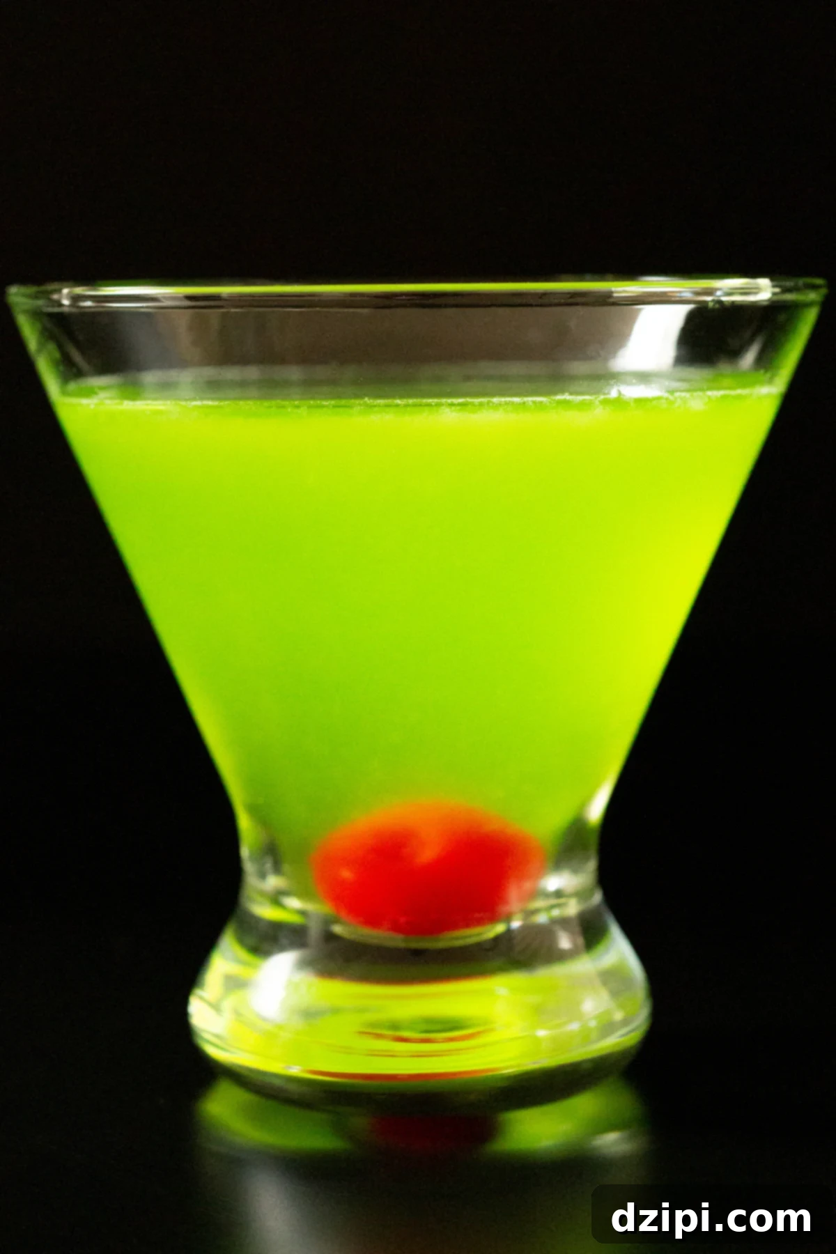 A stemless martini glass with a neon green Japanese Slipper cocktail on a black background.