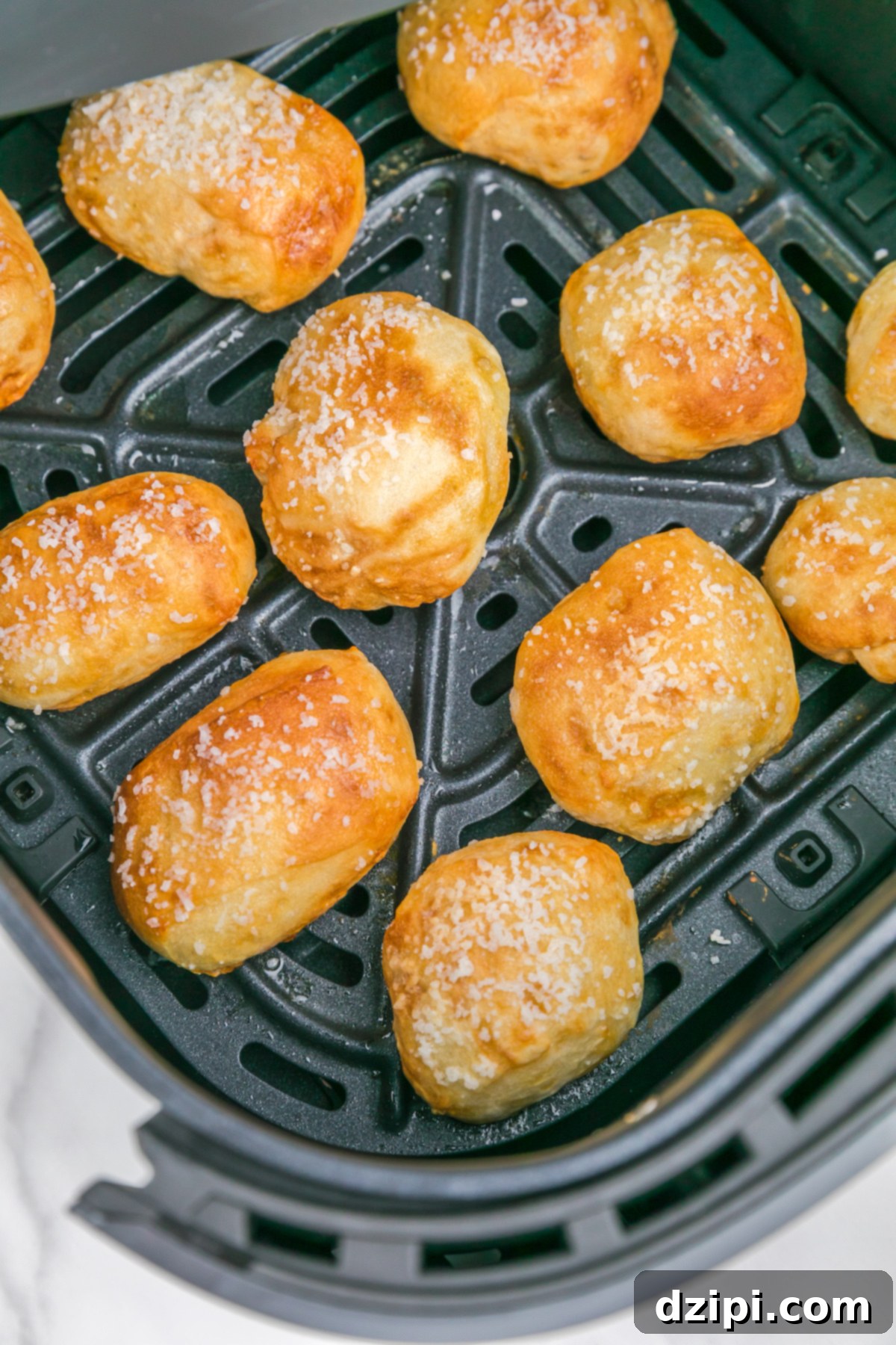 An air fryer basket filled with a batch of perfectly cooked, golden-brown pretzel bites, fresh out of the fryer.