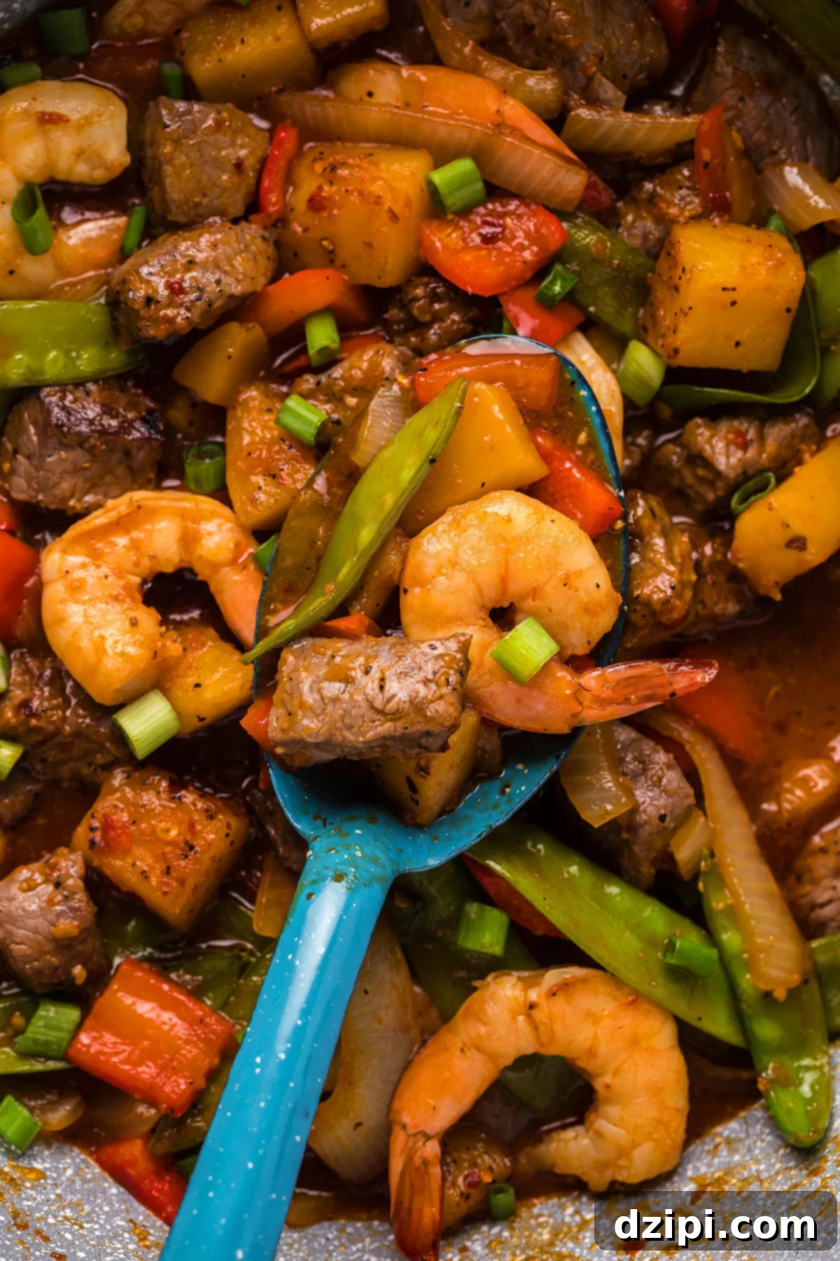 A vibrant skillet filled with perfectly cooked steak bites, tender shrimp, crisp snap peas, and colorful bell peppers, ready to be served.