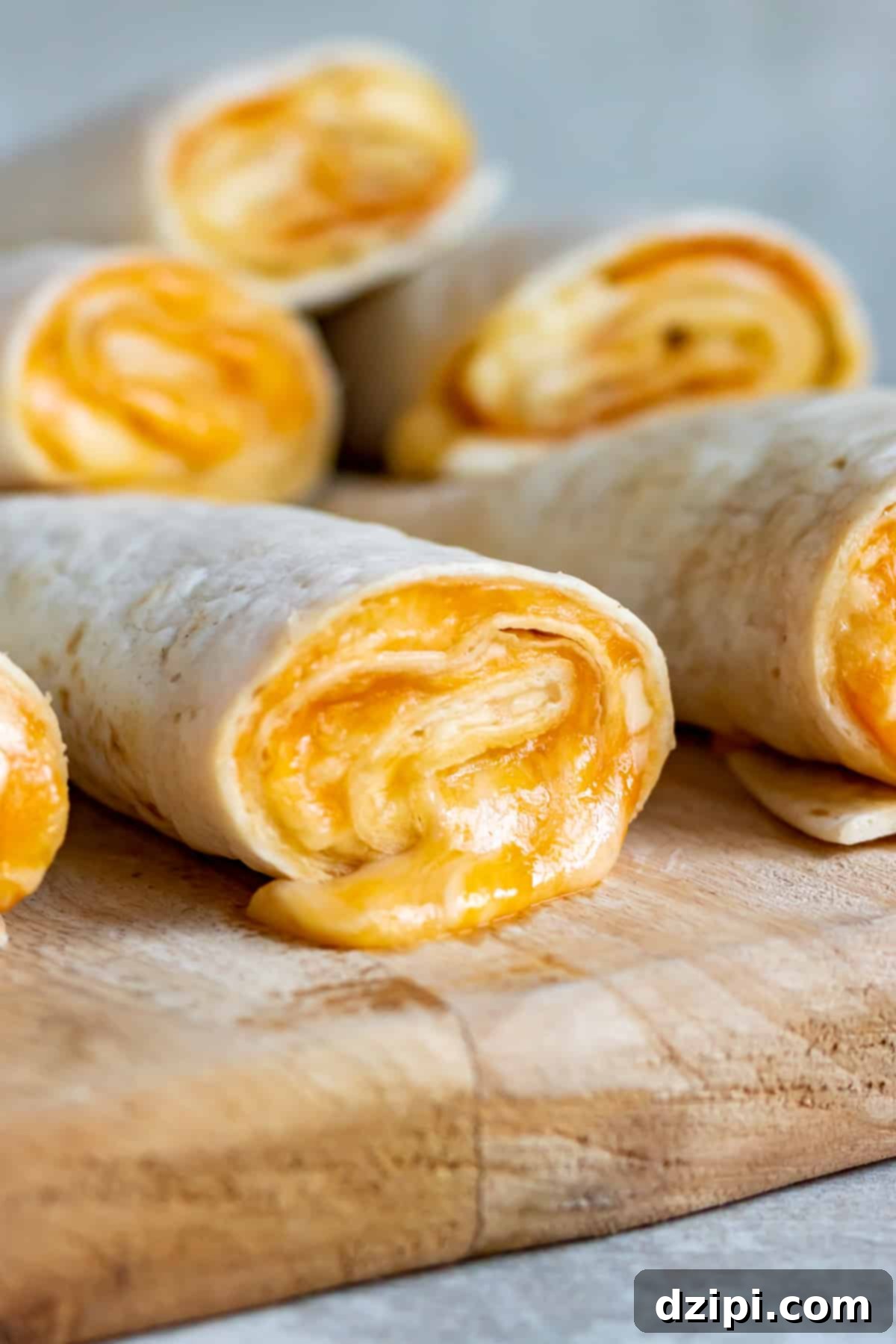 Several golden-brown tortilla roll-ups, generously oozing with melted cheese, arranged on a rustic cutting board.