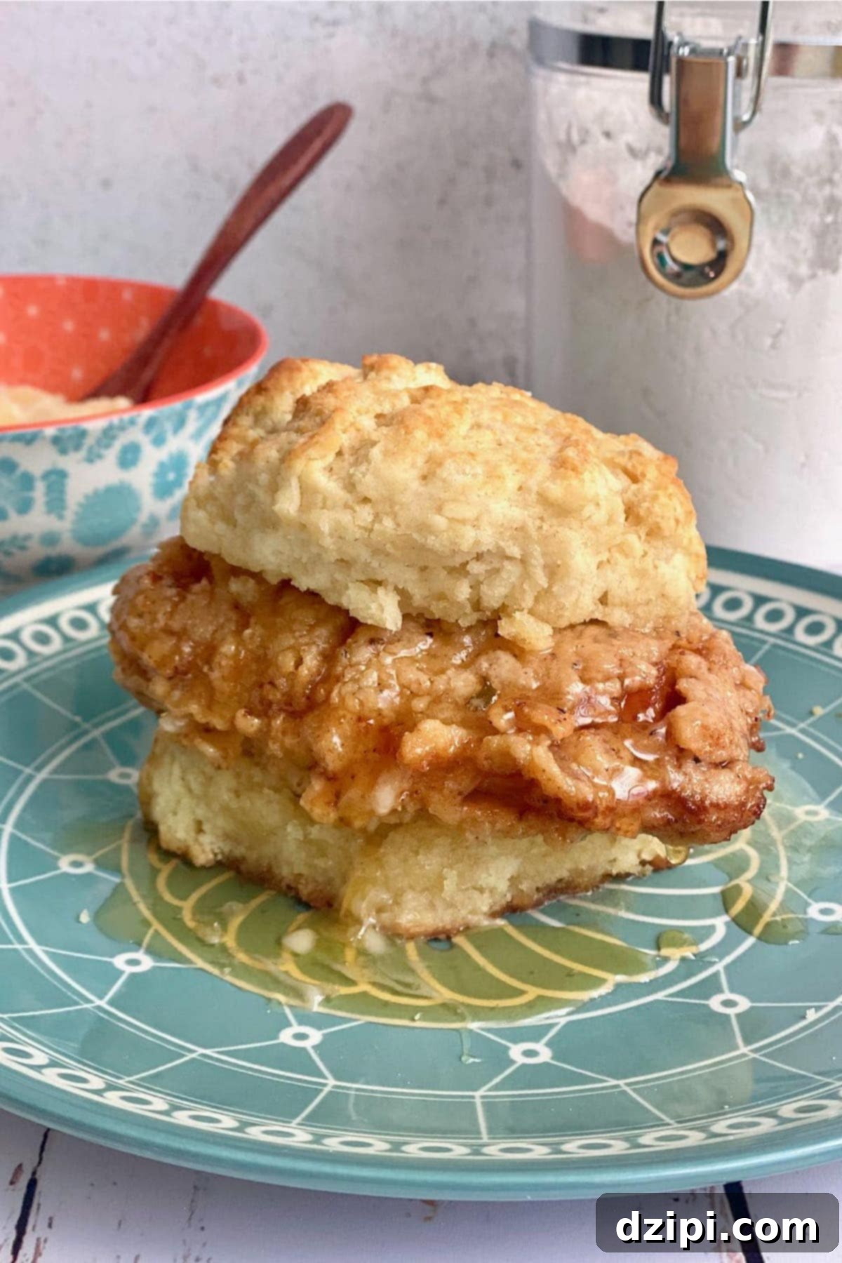 A succulent fried chicken fillet, generously drizzled with golden honey, nestled within a fluffy buttermilk biscuit.
