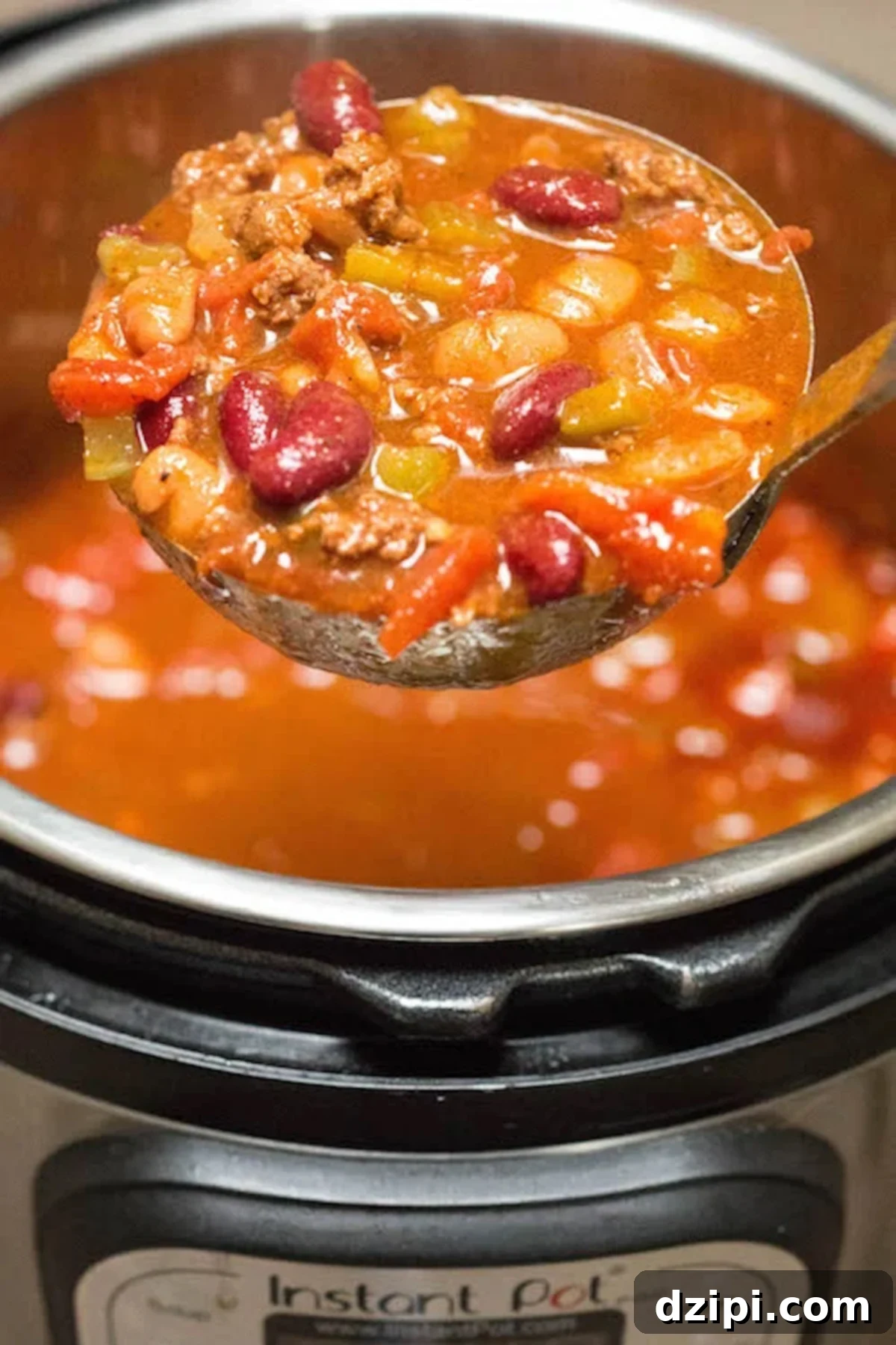 A ladle serving hearty Wendy's chili, with an Instant Pot softly blurred in the background, signaling an easy and quick preparation.