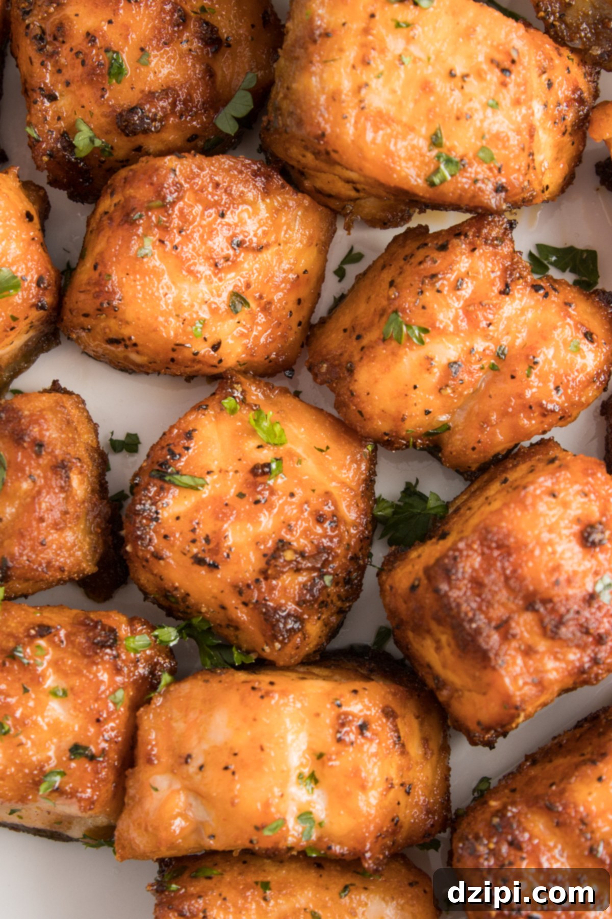 Close up of several air fryer salmon bites garnished with chopped parsley.
