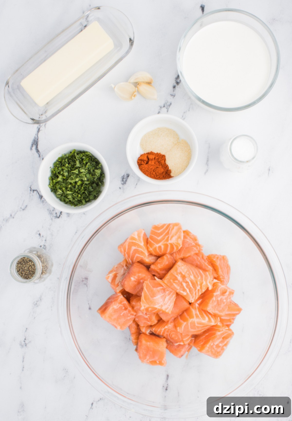All the ingredients needed to make air fryer salmon bites in prep bowls on a marble counter top.
