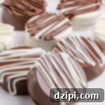 Seven white and milk chocolate covered Oreos on a serving plate. Chocolate chips are out of focus in the background.