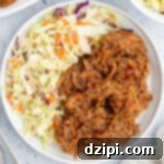 Juicy Instant Pot Pulled Pork 8 Pulled pork covered in bbq sauce and coleslaw on a dinner plate.