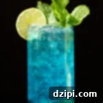 Sapphire Sip 7 A tall glass is filled with pebble ice and a vibrant blue mojito that's garnished with a lime wheel and fresh mint.