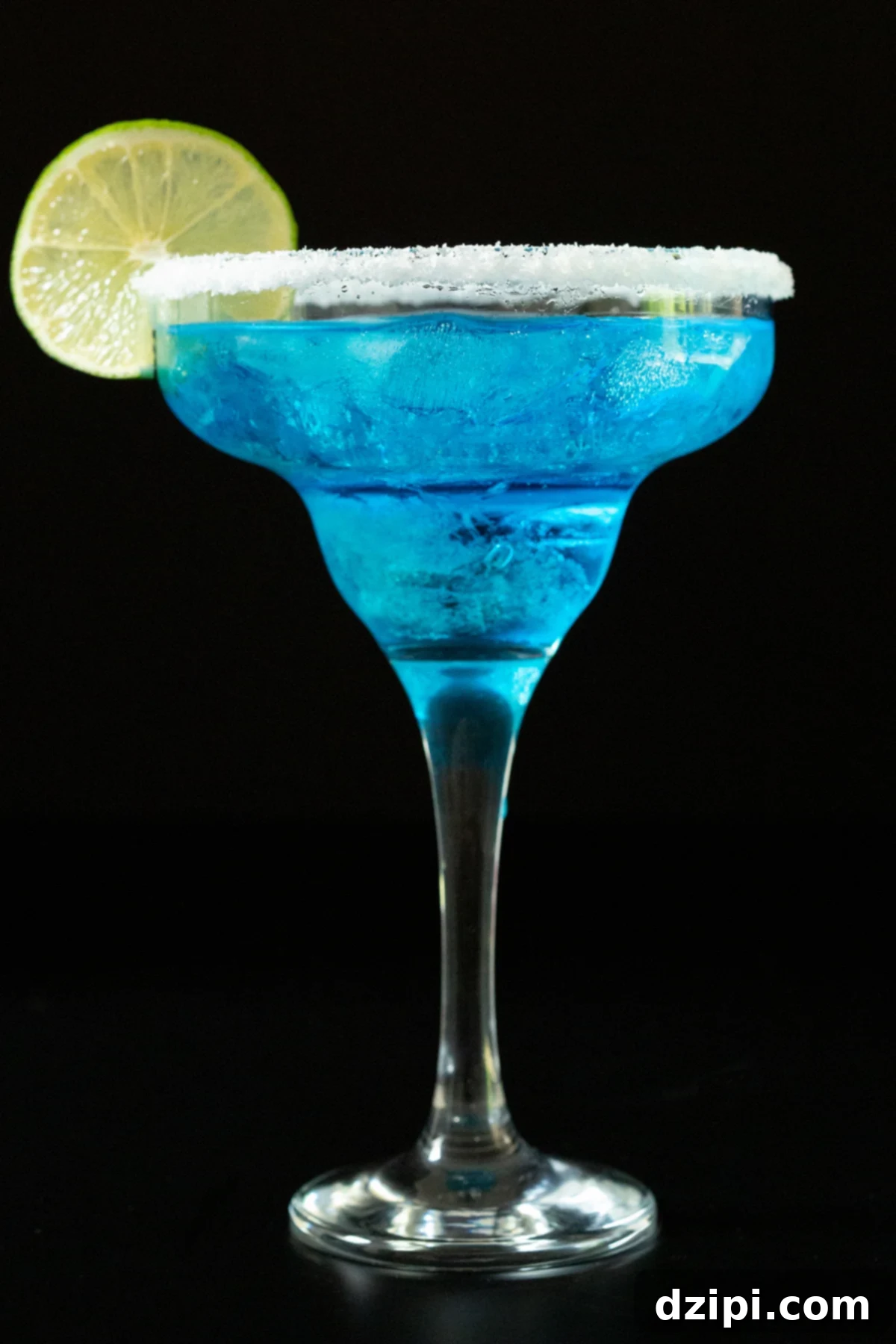 A tall margarita glass is filled with a vibrant bright blue margarita. It's garnished with a salt rim and a lime wheel.