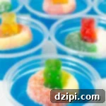 Nine 2oz plastic containers filled with bright blue jello topped with a candy gummy bear and gummy ring, ready for a fun pool party.