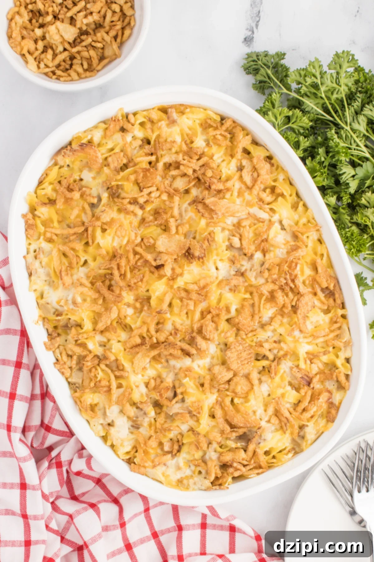 Overhead view of a white baking dish filled with a cooked French onion chicken casserole. A red striped dish towel is in the background.