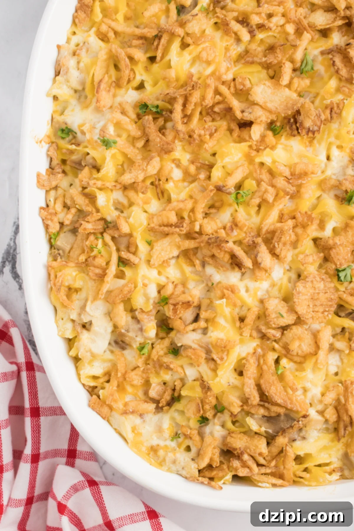 Close up of French onion chicken casserole topped with crispy onions in a white casserole dish.