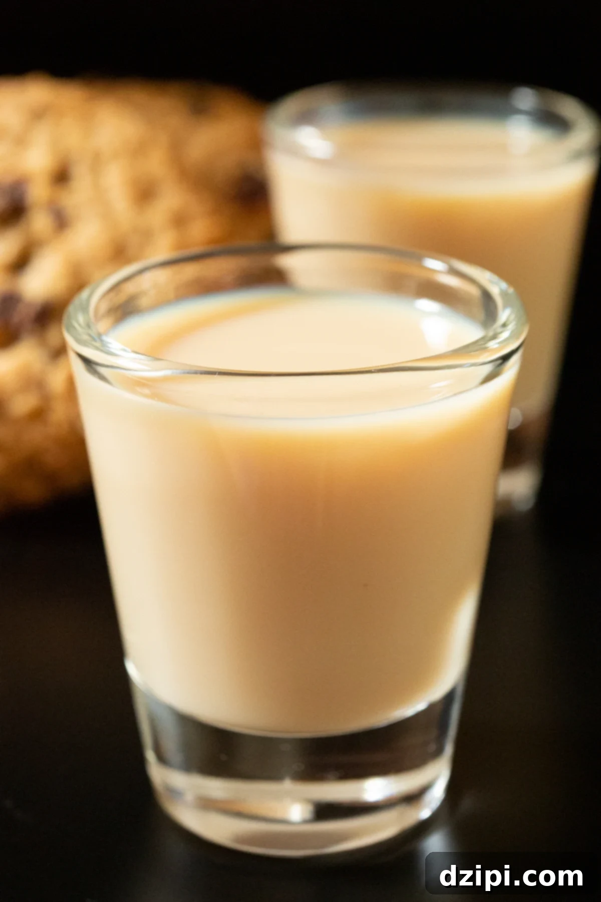 Oatmeal Cookie Cups 6 Two shot glasses filled with creamy brown oatmeal cookie shots. One is in focus and the other in the background out of focus.