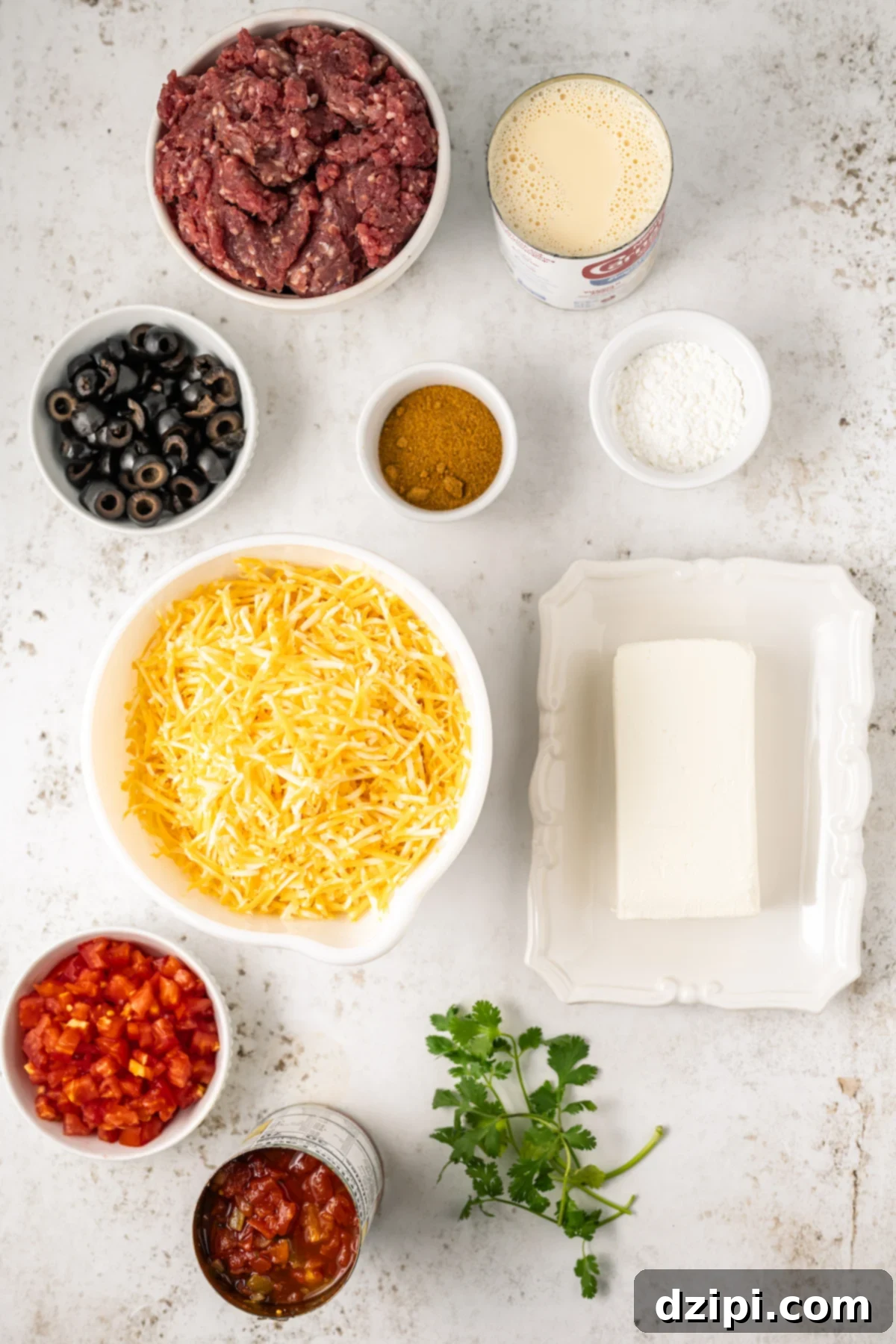 All the necessary ingredients for making Crock-Pot taco dip, neatly arranged in small prep bowls on a pristine white background. Each ingredient is clearly visible and ready for use.
